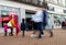 The front of a New Look store in the UK showing logo and shop windows with sale signs and blurred pedestrians walking past