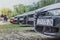 Front nose of an Alfa Romeo 159 in focus, 156 in foreground. Multiple black cars lined up in a field. Parked as a part of an