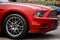 Front part of the exterior of red modern sports car with front fender, bumper, wheel, front light, grille and reflector