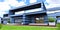 The front part of a futuristic housing. View of the porch and garage with lifting gates. Wonderful green lawn and stylish red