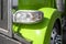 Front part of green big rig semi truck tractor with headlight and chrome grille and wheel