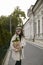 Front portrait of a stylish young woman with a paper pack of green leaf plant on urban city background