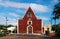 Front of the red colonial church Itzimna in a park with trees, Merida, Yucatan, Mexico