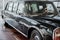 Front and side view of black retro business class limousine with right headlight, chrome mirror and wheel arch on brown