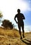 Front silhouette young sport man running cross country workout at summer sunset