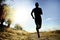 Front silhouette young sport man running cross country workout at summer sunset