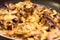 Front top detail of melted cheese, mushrooms and onions on burgers being cooked in a stovetop pan