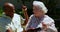 Front view of active mixed-race senior couple using mobile phone in the garden of nursing home 4k