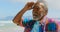 Front view of active senior African American man with hand on chin and hand behind head at beach 4k