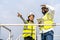 Front view of african american man and woman engineers in uniform discuss use tablet stand near wind turbines ecological energy