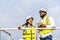 Front view of african american man and woman engineers in uniform discuss use tablet stand near wind turbines ecological energy