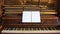 Front view of an antique piano with the keyboard open and two sheets of blank paper on support for musical notes