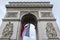 Front view of Arc de Triomp with flag of France waving in wind on Place de Gaulle in Paris, France