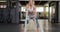 Front view of an athletic Caucasian woman working out with battle ropes