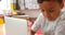 Front view of attentive Asian schoolboy studying with laptop in a classroom at school 4k