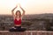 Front view of a back light of a faithful woman in yoga position holding the sun at sunset or sunriset