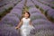 Front view of a beautiful little girl enjoying and running between rows of blooming lavender