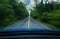 Front view of blue car driving with fast speed on the middle of asphalt road with white and yellow line of traffic symbol