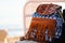 Front View Of Blue Hipster Backpack With White Elephant Pattern And Leather Fringes On Chair By The Beach