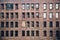 Front view of a boarded-up abandoned brick skyscraper building windows from the street in New York City