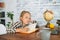 Front view of bored tired cute elementary child school girl doing writing homework holding pen sitting at table with