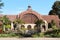 Front view of the Botanical Building with pond, flowers, shrubs and trees framing the building in Balboa Park, San Diego