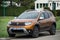 Front view of brown Dacia Duster SUV parked on countryside road