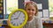 Front view of Caucasian schoolgirl with wall clock sitting at desk in classroom 4k