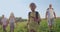 Front view of children walking, going forward, smiling, pathing road, old man behind talking, holding map. Tourists