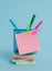 Front view colored sticky note arrow banners stacked metal pens holder lying beautiful pastel background. Blank text
