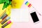 Front view colour pencils smartphone notepads on yellow background. Empty text important future events. What to do home school