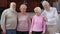 Front view confident positive senior husbands and wives posing indoors smiling. Happy Caucasian men and women standing