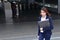 Front view of confident young Asian business woman walking up the stairs at entrance of railway station background.