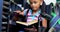 Front view of disabled African American schoolgirl reading a book in library at school 4k