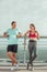 Front view of female and male athletes standing on the city bridge and talking after training