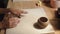 Front view of female potter kneading softly clay on worktop with her hands.