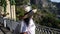 Front view of female tourist in sunglasses and hat exploring Amalfi Coast near Ravello town on sunny day. Beautiful