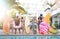 Front view of friends at swimming pool party with lilo airbed and swim wear - Youth vacation concept with happy guys and girls