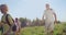 Front view of group of travelers hiking in hills, walking forward, smiling, joking. Old man with gray hair carrying map