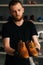 Front view of hands of shoemaker shoemaker in black gloves holding old worn light brown leather shoes to be repaired