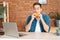 Front view of handsome busy young man eating hamburger watching online cinema on laptop computer sitting at desk in home