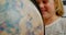 Front view of happy Caucasian schoolgirl studying globe at desk in classroom at school 4k