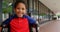 Front view of happy disabled African American schoolboy sitting on wheelchair in school corridor 4k