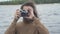 Front view of happy smiling young man taking photo of camera with retro equipment. Portrait of carefree Caucasian