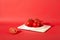 Front view of juicy red tomatoes displayed on a white ceramic plate against a red background. Tomatoes contain antioxidants that