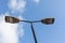 Front view lamp post with two lamps sunny day sky clouds background. Road empty city street. Urban design. Electricity