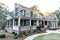 Front view of a large two story blue gray house with wood and vinyl siding