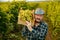 Front view looking at camera elderly winegrower grinding farmer hold box of grapes on his shoulder.