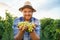 Front view looking at camera young farmer male vintner holding bunch of grapes in hand smiling. The agronomist worker is