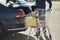 Front view of a man with a shopping cart behind a car with opened trunk outside a supermarket